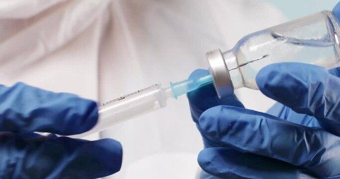 Medical doctor in latex blue rubber gloves holding tube with nCoV Coronavirus vaccine for 2019-nCoV COVID virus.