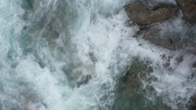 Blue cold water in a mountain river. Slow flight over a fast mountain river in the alps