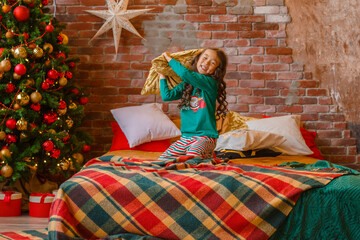 little girl Asian girl in her pajamas in the bedroom messing around on the cushions, Christmas, new year