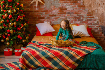 little girl Asian girl in her pajamas in the bedroom messing around on the cushions, Christmas, new...