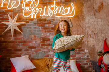 little girl Asian girl in her pajamas in the bedroom messing around on the cushions, Christmas, new...