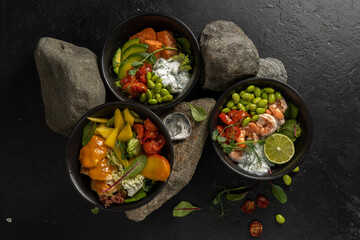 Three black ceramic bowls with assorted vegetarian Asian dishes of fish, shrimp, seafood, beans and avocado with yogurt dressing, lettuce and herbs.