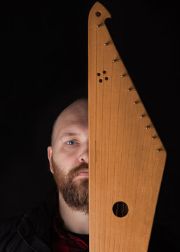 Bearded man hides his face behind Kantele, a national Finnish and Karelian musical instrument, also known as the psaltery (gusli) in Russia and as the kankles, kokle, and Kannel in the Baltic States.