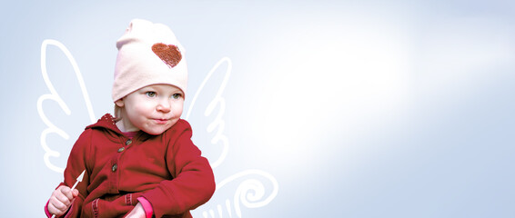 Little Caucasian girl with wings behind her back, smiling and looking cheerfully. Concept child bought it for Valentine's Day.