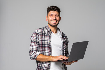 Smiling young man working on his laptop against white background