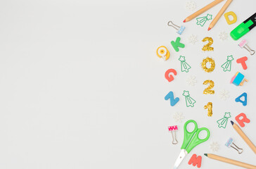 Multi-colored soft English letters, numbers 2021, Christmas tree formed clips, office or school supplies on white background. Back to school, Christmas in office concept. Flat lay, copy space.