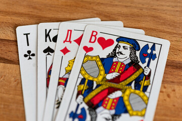 Paper playing cards for playing poker on the background of a wooden brown board.