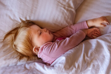Child little girl sleeping in bed. Morning time