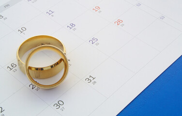 Planning wedding concept. Golden wedding rings on calendar.
