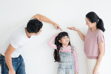 Young happy asian parents playing with their daughter on studio