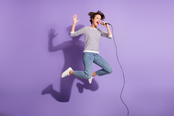 Full length photo of charming lady dressed casual clothes jumping singing microphone isolated...