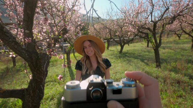 View through viewfinder of analog film camera of young woman posing for photograph. Old school or vintage style of photography, nostalgic images of film. Beautiful model in cherry blossoms