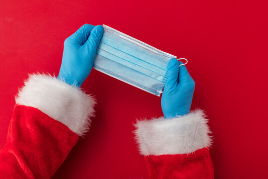 Santa Claus hands holding a coronavirus surgical face mask. Covid Christmas