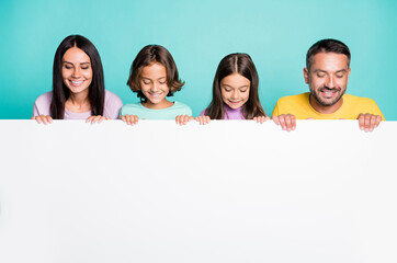 Photo portrait of big family with little kids holding big white paper sheet with copyspace isolated on vivid teal colored background