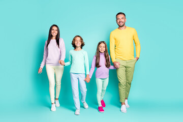 Fototapeta premium Photo portrait of full family walking forward holding hands isolated on vivid teal colored background