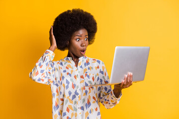 Photo of shocked dark skin woman wear casual outfit looking holding modern device arm head isolated yellow color background