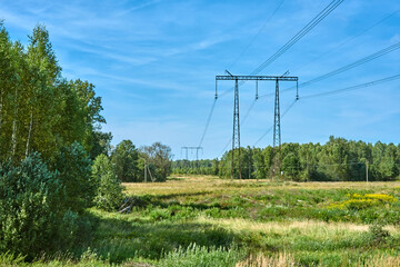 Power transmission line support against the background of a field and forest