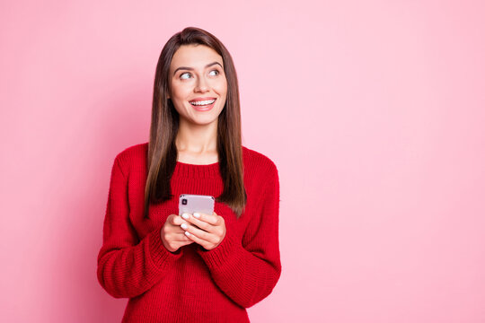 Photo of charming girl hold telephone look up empty space wear red sweater isolated pink color background