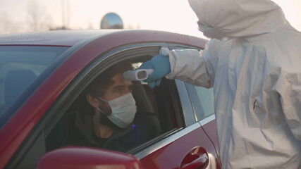 Doctor using infrared thermometer gun to check body temperature of driver