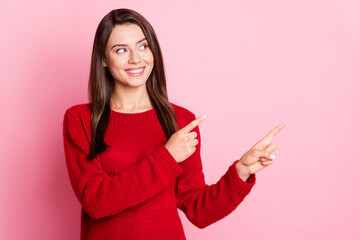 Photo portrait of beautiful smiling brunette wearing warm sweater pointing on copyspace space with both hands looking at side isolated on pink color background