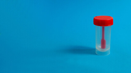 closed plastic red container for collecting feces on a blue background side view . analyzes