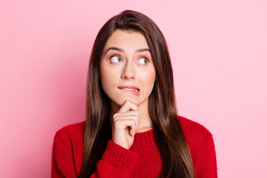 Portrait photo of pretty guilty female student biting lip touching chin thinking about solution of problem isolated on pink color background