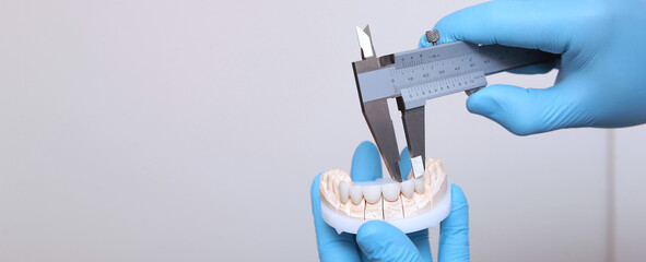 A dental technician makes the measurement of the veneers. Ceramic and composite veneers. Hands in...