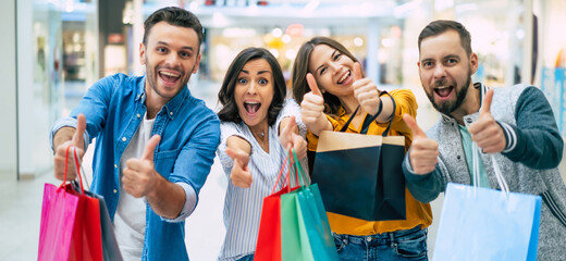 Happy company of smiling excited beautiful stylish friends with colorful paper bags are having fun...