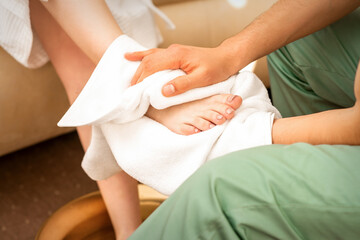 Masseur wiping the woman's legs after a foot massage in the spa salon