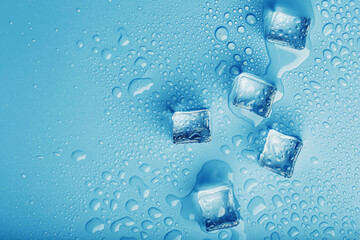 Ice cubes with water drops scattered on a blue background, top view.