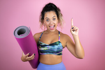 Young beautiful woman wearing sportswear and holding a splinter over isolated pink background surprised with her finger raised having an idea.