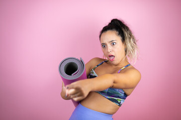 Young beautiful woman wearing sportswear and holding a splinter over isolated pink background...