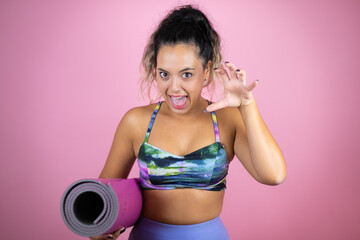 Young beautiful woman wearing sportswear and holding a splinter over isolated pink background...