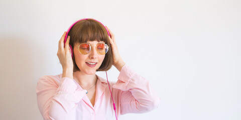 Young happy woman in pink shirt with headphones engrossed in listening to the music.