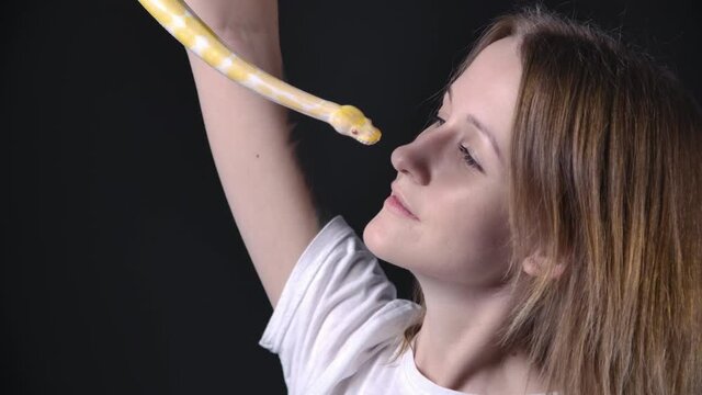 Slow motion footage of blond woman with albino python near face
