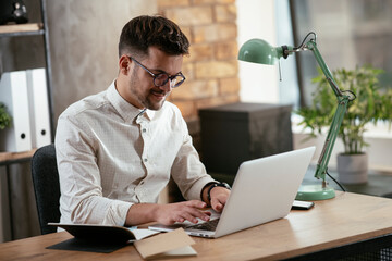 Obraz premium Businessman working in the office on his laptop. Stylish businessman working on a project in the office.