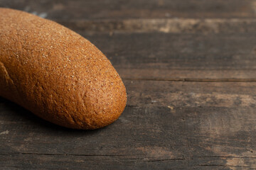 Freshly baked traditional black bread on a wooden table. brown coarse bread made from shenitsa, barley, rye flour.