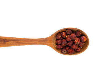 Dried red Crataegus curvisepala Crataegus monogyna, Crataegus rhipidophylla known as common hawthorn or single-seeded hawthorn berries on spoon, isolated on white background.