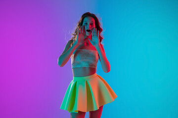 Emotions. Beautiful seductive girl in fashionable yellow skirt on gradient pink-blue neon background. Half-length portrait. Copyspace for ad. Flyer design. Summer, fashion, human emotions concept.