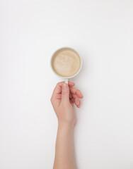 Fototapeta premium Women's hands hold a white Cup of cappuccino or cocoa. The view from the top.