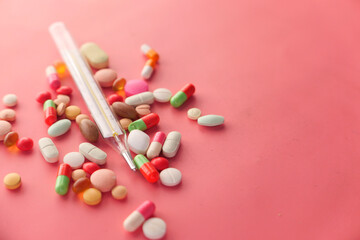 medical thermometer and pills on pink backgrund 