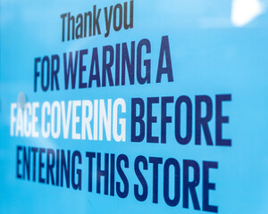 A close up of a sign on a shop window thanking customers for wearing a face covering when entering a shop