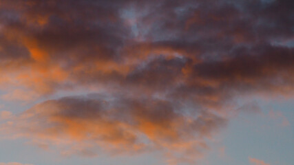 Fototapeta na wymiar Magnifiques teintes orangées observées sous des cumulus fractus, pendant le coucher du soleil
