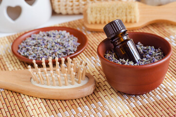 Small bottle with essential lavender oil (extract, tincture, infusion, perfume) and wooden hair brush. Aromatherapy, spa and herbal medicine ingredients.