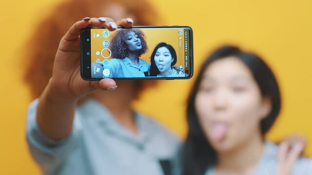 Two young girls, lesbian couple using smartphone to take photo. Making grimaces. High quality 4k footage