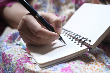 Close up of women hand writing on notepad.