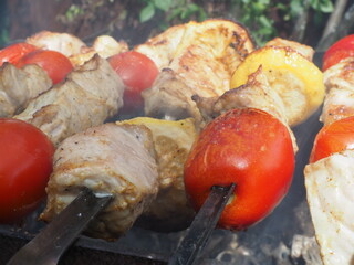 pork skewers with tomatoes and lemon grilled on the grill with smoke