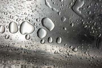 Stainless metal kitchen sink macro close up shot with big water droplets and scratched surface texture