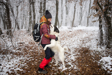 woman with dog walking in frost covered forest in winte