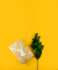 Christmas composition, gift wrap with deer and fir branches, yellow background, template, top view, copy space